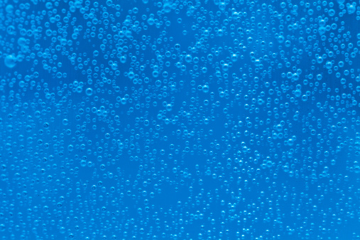 Carbonated bubbles on a blue background. Shallow depth of field.
