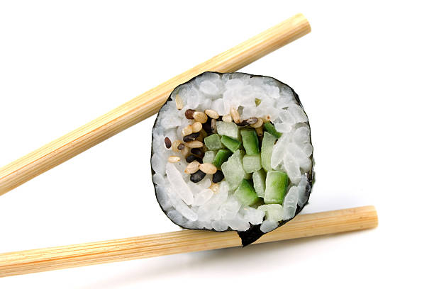 Wooden chopsticks holding vertically a slice of sushi stock photo