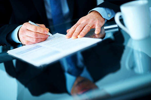 Businessman hand signing contract paper at the desk stock photo