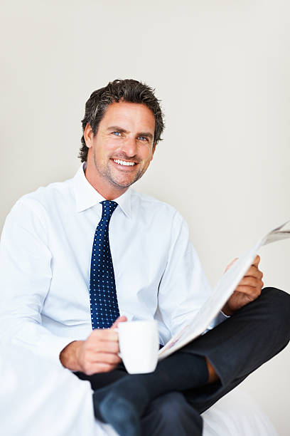 istock Man sitting on bed with coffee and newspaper 184122481