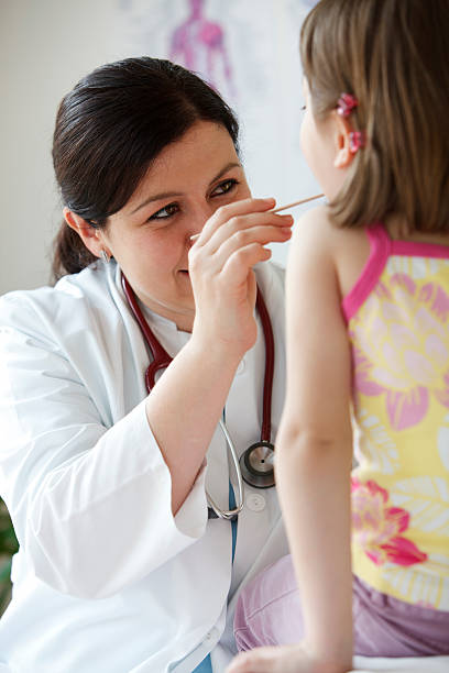 istock Female pediatrician checking child's throat 184122567