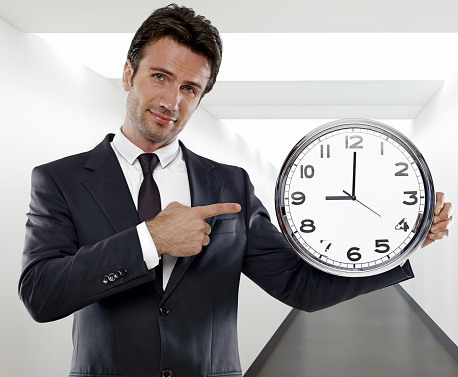 Crazy happy bearded man with tousled hair, in glasses holding big clock, isolated on white background.