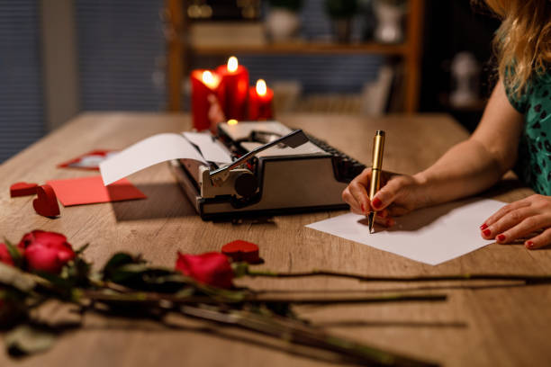 liebevolle frau, die an ihrem schreibtisch sitzt und einen romantischen liebesbrief zum valentinstag schreibt - love flower single flower letter stock-fotos und bilder