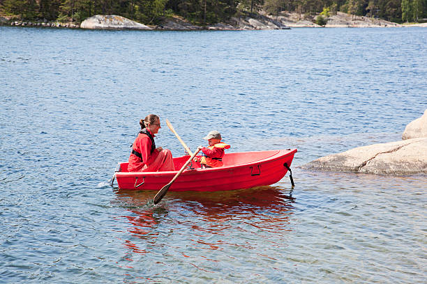 mutter und sohn in kleine rote ruder boot. stockholm-archipel. - stockholmer archipel stock-fotos und bilder