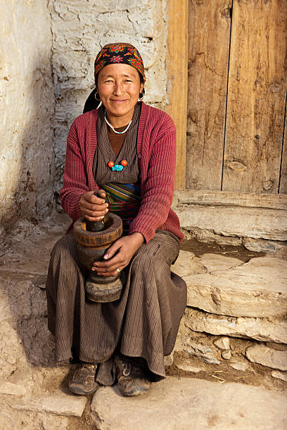 istock Tibetan woman using a mortar to make  flour. Mustang, Nepal 184131286