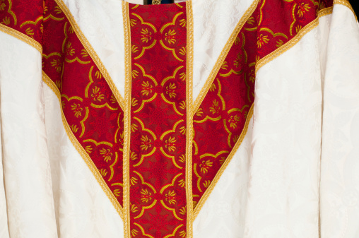 Detail of a priest's white cloth with red ribbons. Horizontal format.