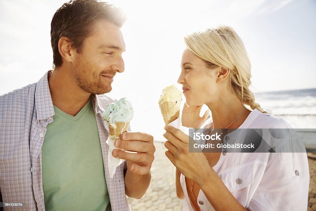 Young couple enjoying an ice cream on the beach Portrait of cute young couple enjoying an ice cream on the beach Ice Cream Stock Photo