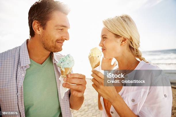 Young Couple Enjoying An Ice Cream On The Beach Stock Photo - Download Image Now - Ice Cream, Couple - Relationship, Eating