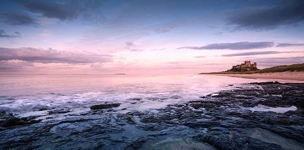 bamburgh castle bei sonnenaufgang - bamburgh stock-fotos und bilder