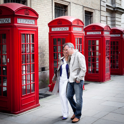 Mature couple walking with public English telephone booth on the background. WPO and iStockalypse London 2011.