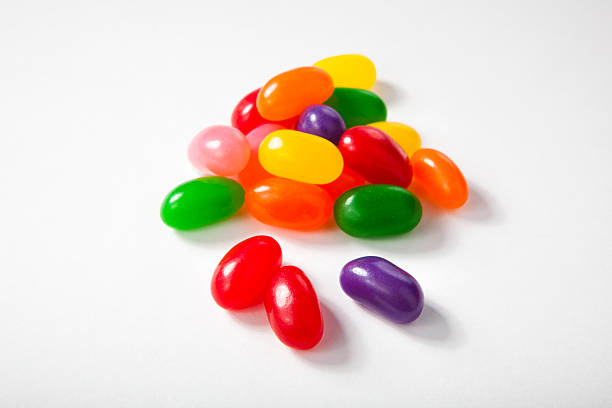 Close up of a delicious Jelly Beans candy spilled from a glass jar isolated on a white background