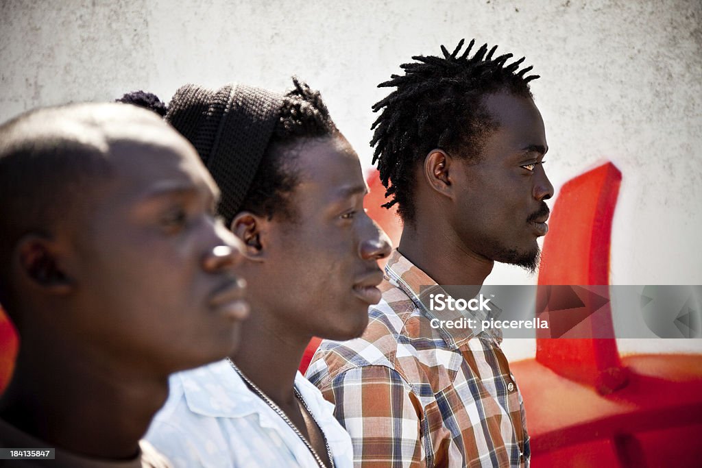 Três africanos homens em uma fileira, olhando no horizonte - Foto de stock de Desfocado - Foco royalty-free