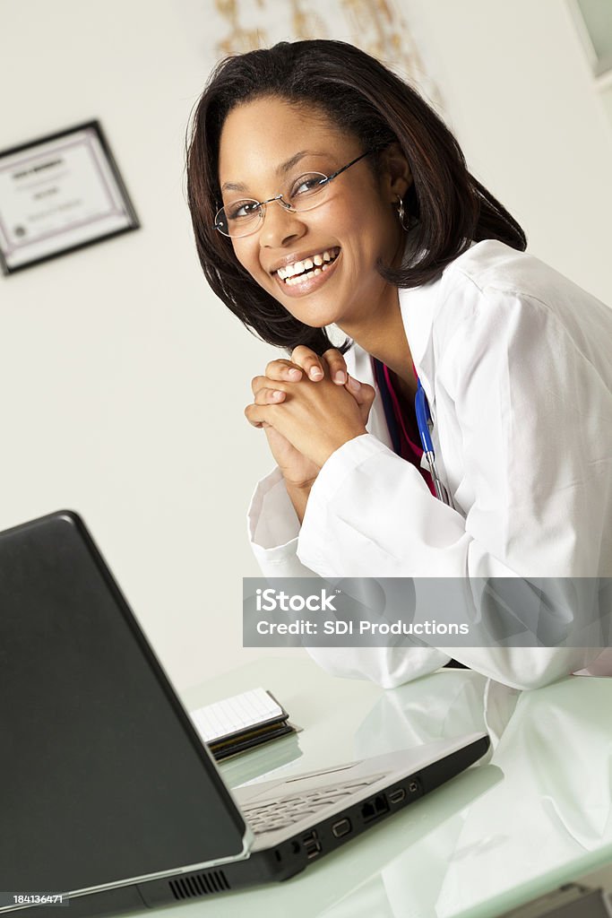 Sonriendo médico sentado en su escritorio - Foto de stock de Adulto libre de derechos