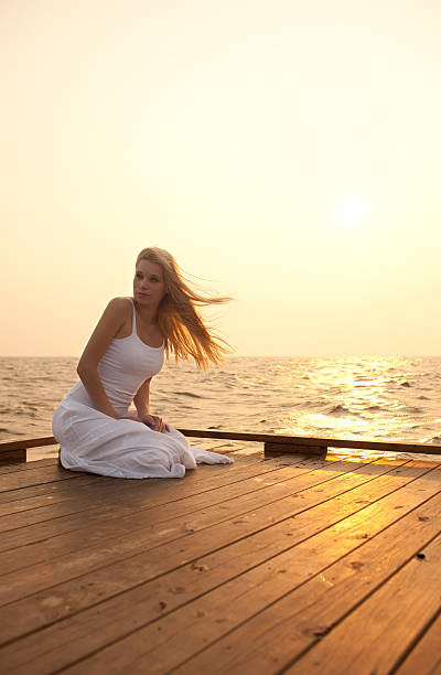 istock Young woman sitting on the pier 184138166