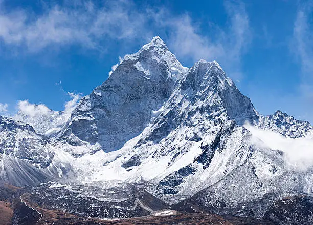 Ama Dablam is a mountain in the Himalaya range of eastern Nepal. The main peak is 6,812  metres (22,349 ft), the lower western peak is 5,563 metres (18,251 ft). Ama Dablam means  "Mother's neclace"; the long ridges on each side like the arms of a mother (ama) protecting  her child, and the hanging glacier thought of as the dablam, the traditional double-pendant  containing pictures of the gods, worn by Sherpa women. For several days, Ama Dablam dominates  the eastern sky for anyone trekking to Mount Everest basecamp.http://bhphoto.pl/IS/nepal_380.jpg