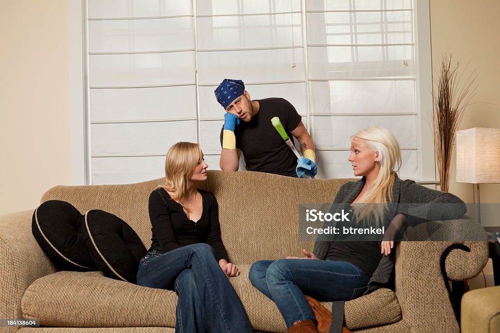 Stressed husband + 'house man' Reversed gender roles - stressed husband has to handle baby and clean the house. While his wife is having a fun time with a friend Bandana Stock Photo