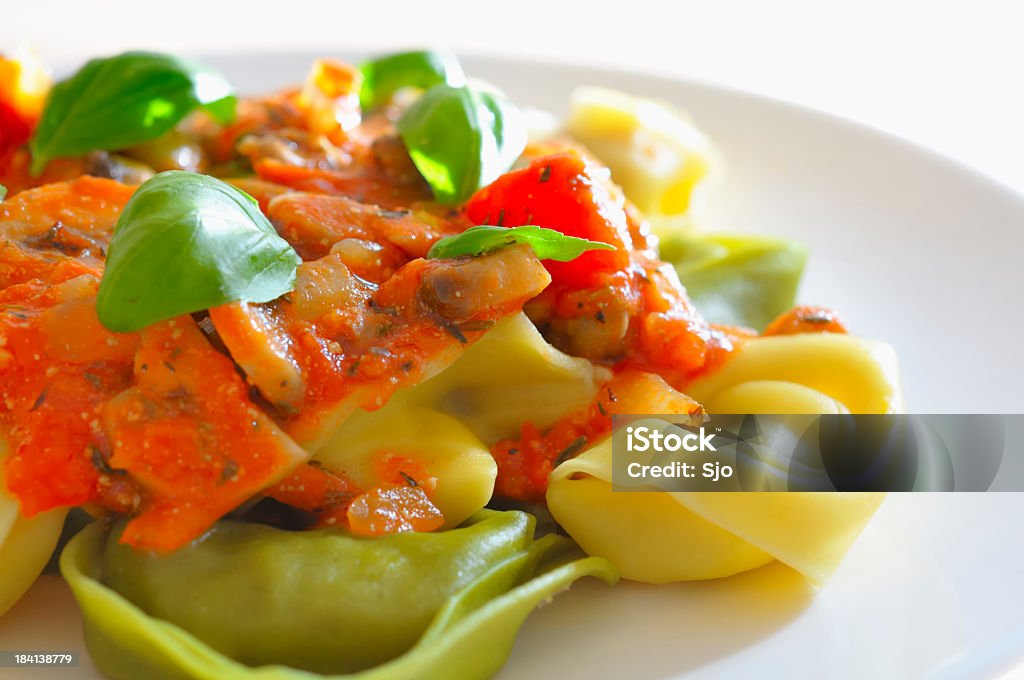 Un primo piano di una salsa di pomodoro e basilico tortellini su bianco - Foto stock royalty-free di Tortellini