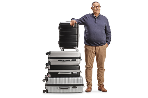 Mature man leaning on a pile of suitcases isolated on white background
