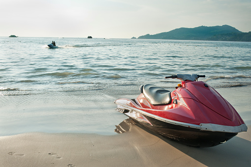 Red jet ski on the beach at the water's edge.