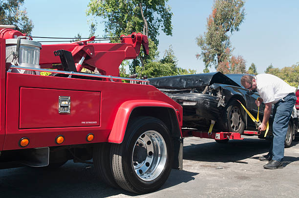 tow truck driver hauling a wrecked car - sleep stockfoto's en -beelden