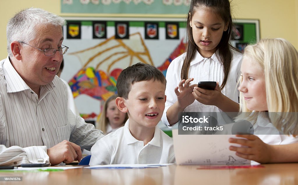 junior school: education matters "A group of junior school pupils working together on a group project under the encouraging eye of their class teacher.Candid, waist-up portrait." 40-49 Years Stock Photo