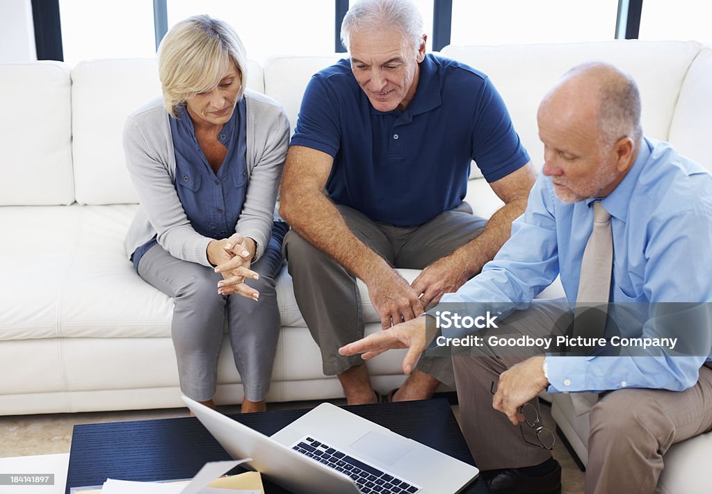 Senior man explaining about investment plan on laptop Financial planner explaining a investment plan on laptop to elderly couple at home 50-59 Years Stock Photo