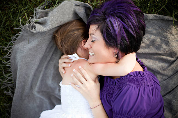 istock Mother and Daughter Hugging While Laying in Grass 184143417