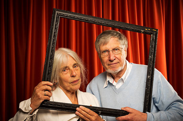 istock Senior couple holding picture frame 184143620