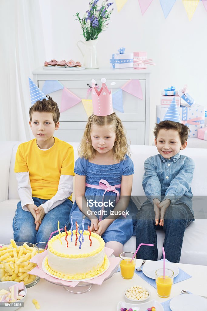 Siblings at a birthday party "Sister and her brothers having birthday party, sitting on sofa in domestic room. Birthday table with a birthday cake in the foreground, lots of gifts in the background." Birthday Stock Photo