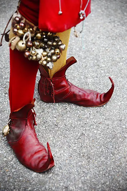 Funny red boots of a medieval court jester with jingle bells.