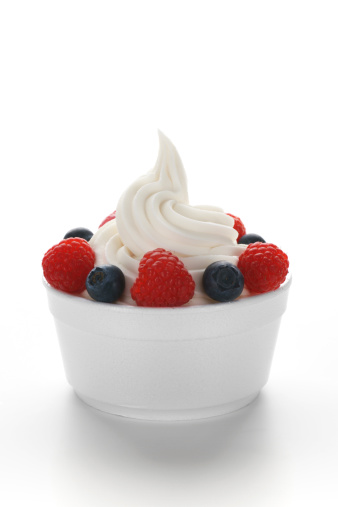 Single serving of frozen yogurt (or soft serve ice cream) with raspberries and blueberries in a standard disposable restaurant portion cup.