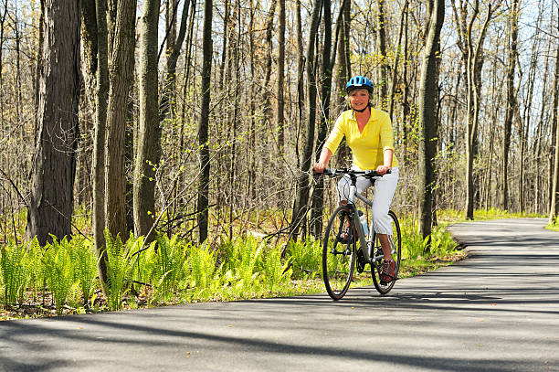 Two bicyclists bicycling on a park bike path in Autumn color. Young Caucasian man and a black American young woman exercising together in a nature park together. Photographed on location in Minneapolis,f Minnesota, USA in horizontal format with available copy space.