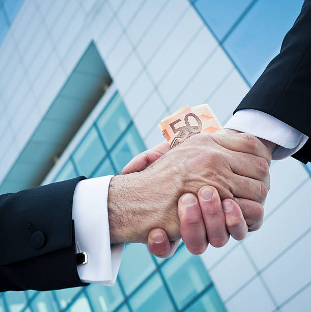 zwei korrupte männer beim händeschütteln gegen eine moderne wolkenkratzer - asset management scam stock-fotos und bilder