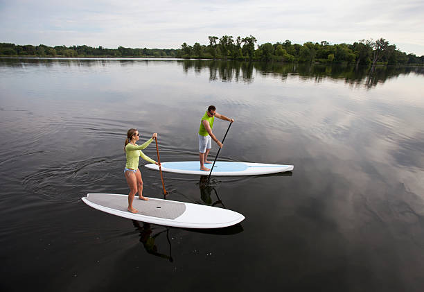 coppia atletica canoa su un lago tranquillo del midwest. - paddleboard oar women lake foto e immagini stock