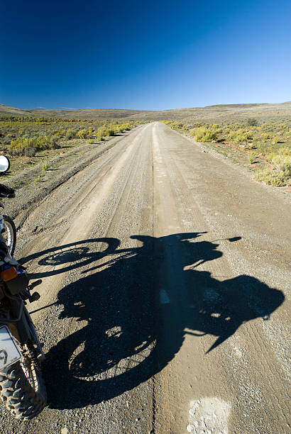 istock shadow of motorcycle on dirt road 184151686