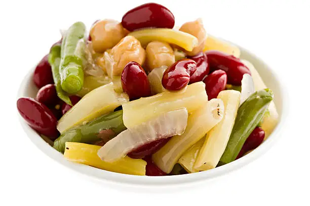 An overhead close up of a small white  bowl containing a portion of four bean salad. Isolated on white.