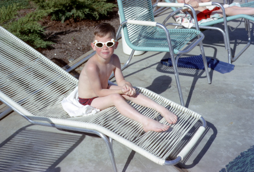 Small boy enjoys summertime sunshine wearing duck sunglasses.  Retro circa 1964.