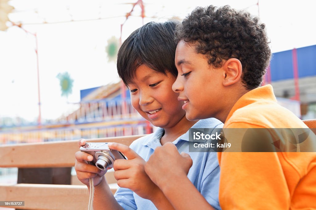 Boys playing with digital camera "Multiracial boys looking at screen on digital camera, 9 and 10 years." Camera - Photographic Equipment Stock Photo