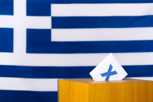 Ballot in a ballot box. The national flag of Greece in the background.
