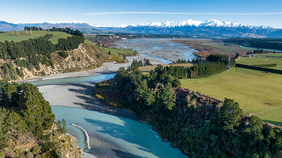 The bright blue transparent water in the Waimakariri river flowing through the rural Gorge in agricultural farmland  in the  Canterbury Region of New Zealand