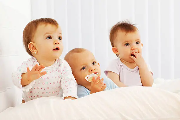 Cute babies playing on the bed.