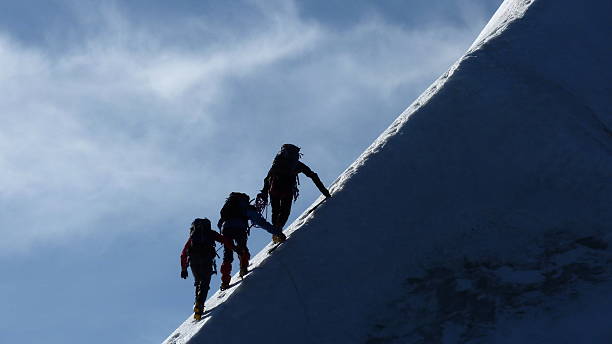 bergsteiger auf einem steilen mountain ridge - bergkletterer stock-fotos und bilder