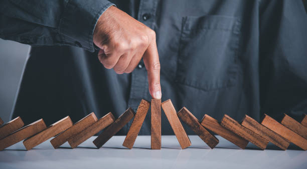 Close up hand stopping or preventing falling block in line with risk project control