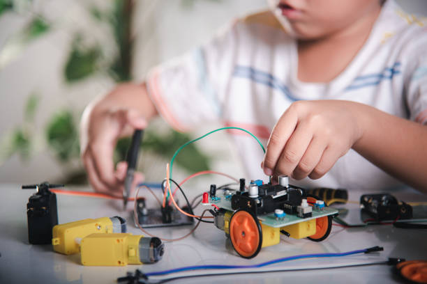 Little child remotely learn online with car toy before sent code, Asian kid boy plugging energy and signal cable to sensor chip with robot car, STEAM education AI technology course learning