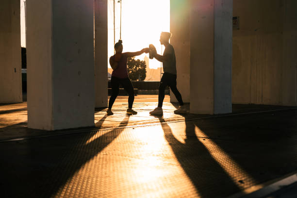 Pacific Islander people in casual clothing training boxing outdoor in togetherness.