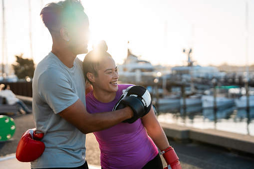Happy boxing couple wearing boxing gloves embracing each other outdoors.