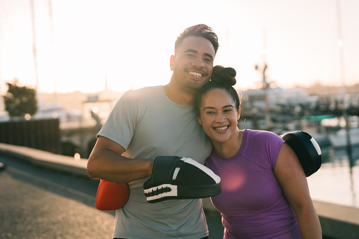 The portrait of happy Pacific Islander couple wearing boxing gloves smiling at camera.
