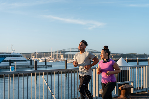 Couple outdoor jogging in Auckland City with Harbor bridge in background.