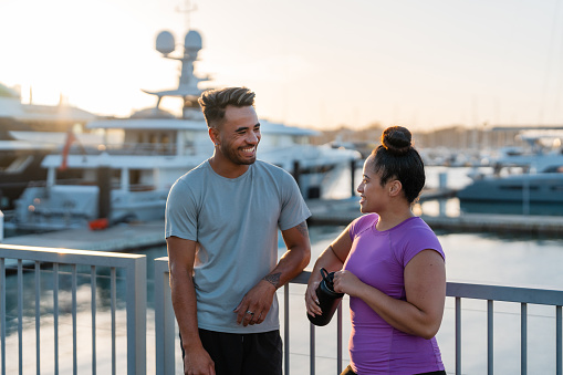 Happy Pacific Islander couple outdoors gossiping and taking rest after workout.