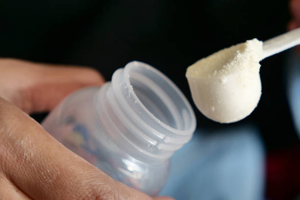 Making baby formula milk at night, close up pouring powder into bottle